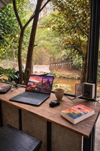 a desk with a laptop and a mouse and a book at 1000 Stars Riverside Hostel in Ban Khrae Yao Doi Bo
