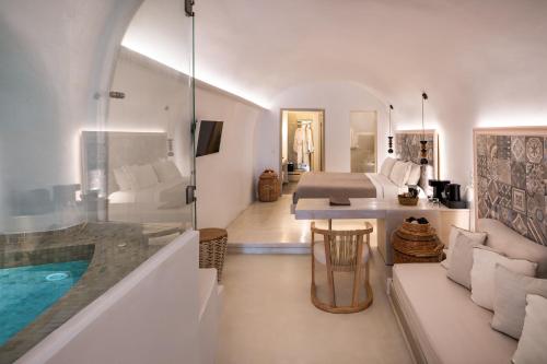 a bedroom with a tub and a bed and a bath room at Athina Luxury Suites in Fira