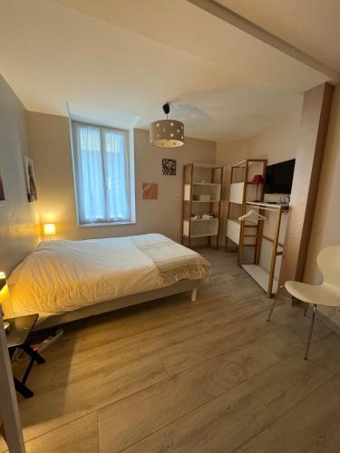 a bedroom with a bed and a desk and a window at Studio Cosy avec Cour Privée in Fleury