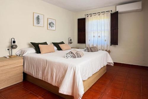 a bedroom with a bed with white sheets and a window at Casa El Colmenero in Garafía