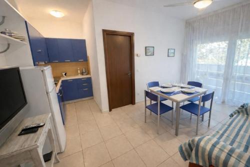 a kitchen and dining room with a table and blue chairs at Residence Patty in Caorle