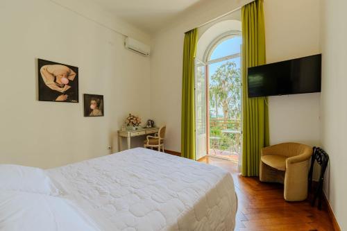 a bedroom with a white bed and a window at Promenade Maison de Charme in Sanremo