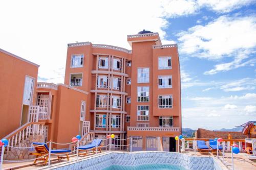 a large apartment building with a swimming pool and chairs at Maya Holiday Point in Ogembo
