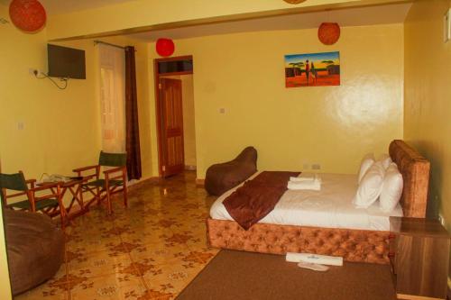 a hotel room with a bed and a table and chairs at Maya Holiday Point in Ogembo