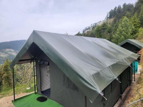 a tent on top of a hill with trees at New Kufari Apple Valley camping in Shimla