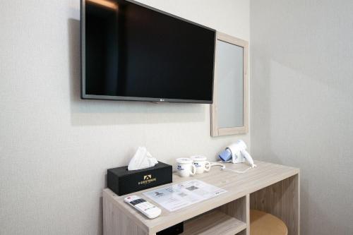 a room with a tv on a wall with a table at K-Guesthouse Premium Nampo 1 in Busan