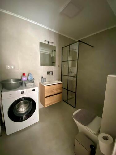a bathroom with a washing machine and a sink at Nikol's central suite 2 in Nea Peramos