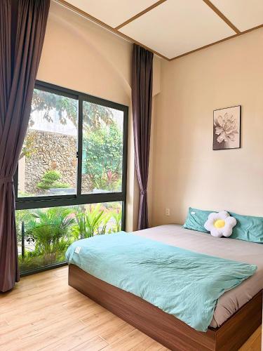 a bedroom with a bed and a large window at K'TY Homestay Phan Thiết in Ấp Bình Hưng
