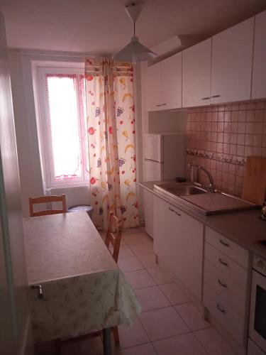 eine Küche mit weißen Schränken, einer Spüle und einem Fenster in der Unterkunft Chambre D in Biel