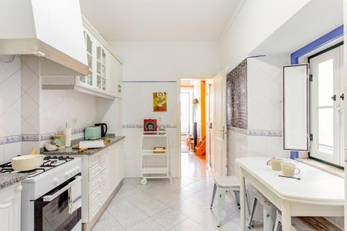 a kitchen with white cabinets and a table in it at Baixa Heritage Apartments by Cathedral & Tram 28 by NestAtLisbon in Lisbon