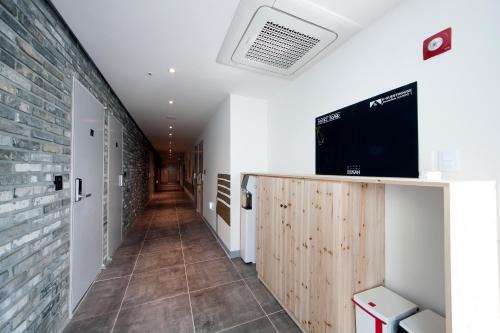 a hallway with a tv on a wall at K-Guesthouse Premium Nampo 1 in Busan