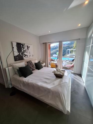 a bedroom with a large white bed with a large window at VILLA COLINA Cannes Mandelieu in Mandelieu-La Napoule