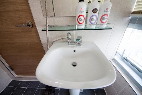 a bathroom with a white sink and bottles of soap at K-Guesthouse Premium Nampo 1 in Busan