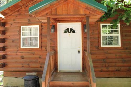 a log cabin with a white door and windows at Jack Pine Hollow in Logan