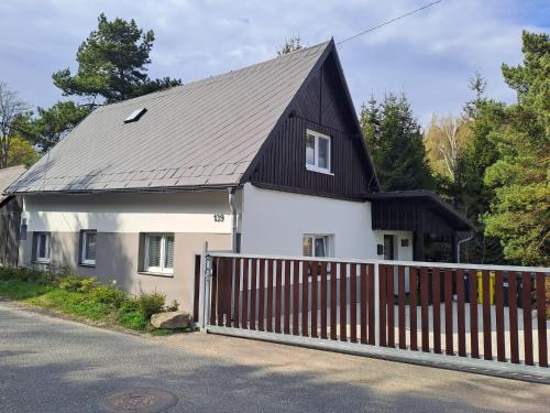 a white house with a black roof and a fence at Chalupa na lužické stezce in Svor