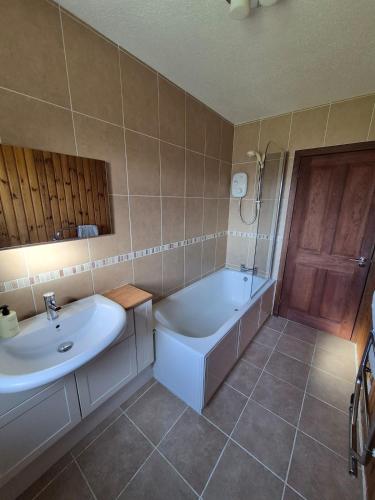 a bathroom with a tub and a sink and a bath tub at Quholmslie Farm Self-Catering in Stromness