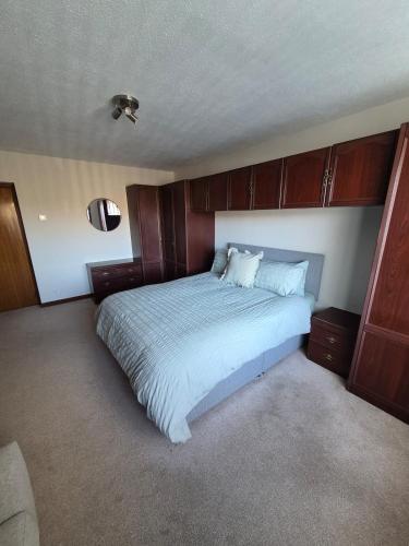 a bedroom with a large bed with wooden cabinets at Quholmslie Farm Self-Catering in Stromness
