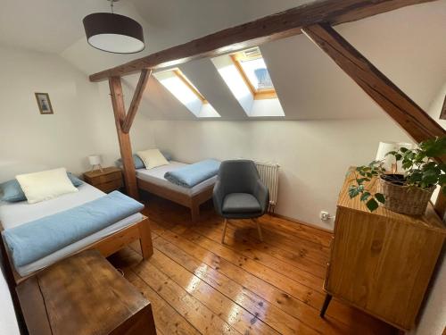 a attic room with two beds and a chair at Tyllichova Chata in Hejnice