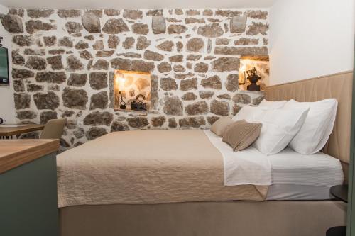 a bed in a room with a stone wall at Apartmani Kostic in Tivat