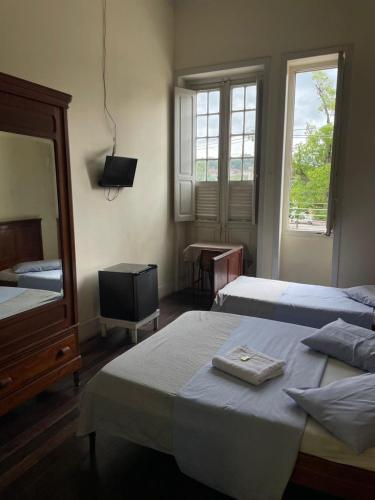 a bedroom with two beds and a mirror and a television at Hotel Valenciano in Valença