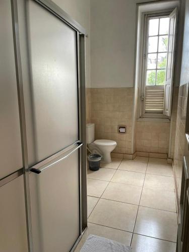 a bathroom with a toilet and a glass door at Hotel Valenciano in Valença