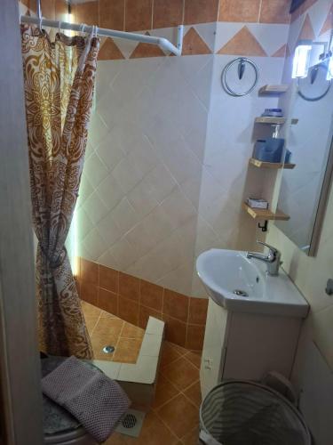 a bathroom with a shower curtain and a sink at Le Rocher 3 in Ermoupoli