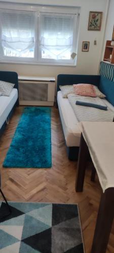 a room with two beds and a table and rug at Adikati Lak in Bük