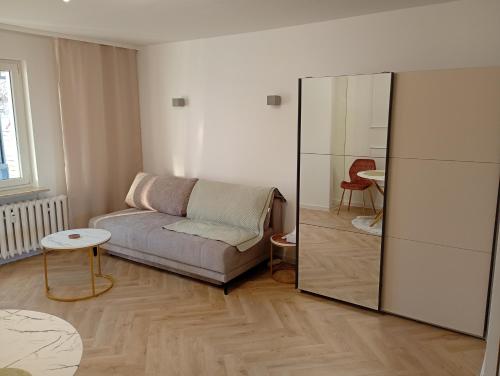 a living room with a couch and a mirror at Apartament Niebieskie in Zamość