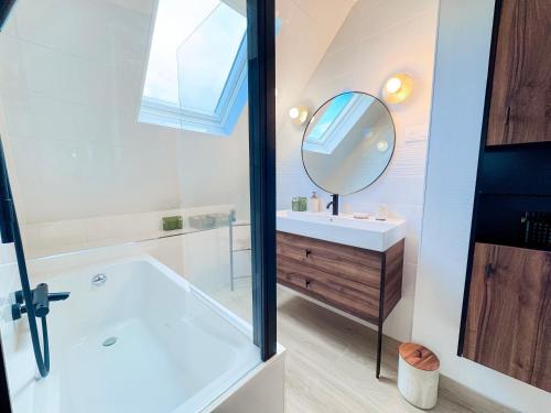 a bathroom with a tub and a sink and a mirror at Ty ar Vigouden - maison de vacances in Loctudy