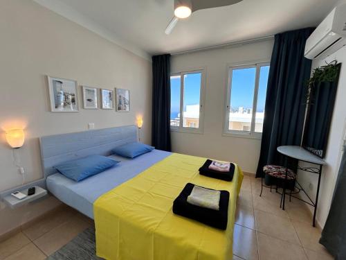 a bedroom with a large bed with a yellow blanket at Akamas Bayview Apartment in Neo Chorio