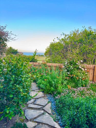 a garden with a stone walkway with flowers and a fence at Cadwalader House in Sea Ranch