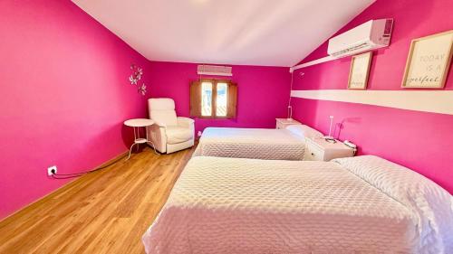 a room with three beds and a pink wall at Casa Rural NEREA in Letux