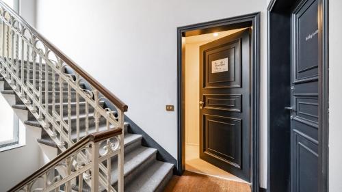 a hallway with a black door and stairs at Mariposa in Lecco