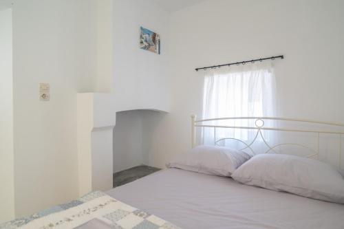 a bedroom with a bed with white sheets and a window at Xenia's House in Kefalos