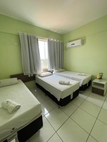 ein Schlafzimmer mit zwei Betten und einem Fenster in der Unterkunft Hotel Letiva Arco in Sobral