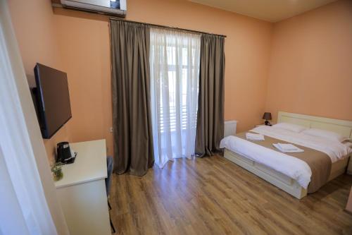 a bedroom with a bed and a tv and a window at Prime Heaven in Chiatʼura