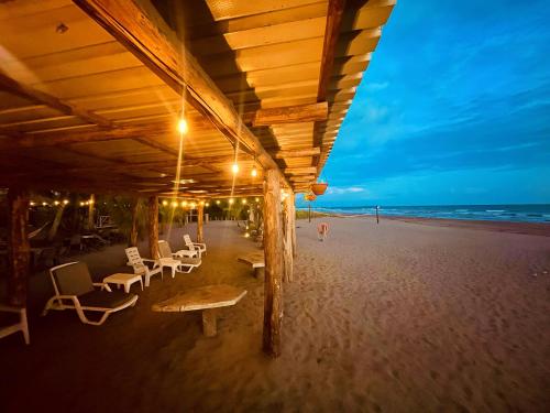 a beach pavilion with chairs and tables on the beach at Show Pony Ranchero Resort - Boutique Beach Hotel in Las Lajas