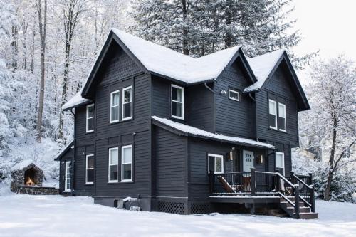 a black house with snow on the roof at Pinetree Guesthouse in Fleischmanns
