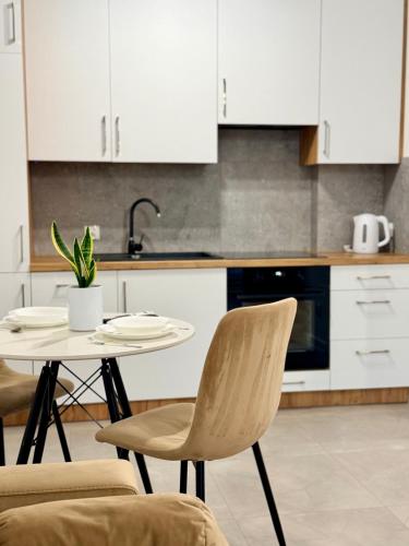 a kitchen with a table and chairs and white cabinets at Apartament KJ Tomice in Tomice