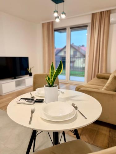 a white table in a living room with a plant on it at Apartament KJ Tomice in Tomice