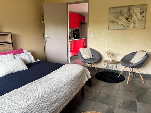 a bedroom with a bed and two chairs and a table at La croisée des chemins in Vions
