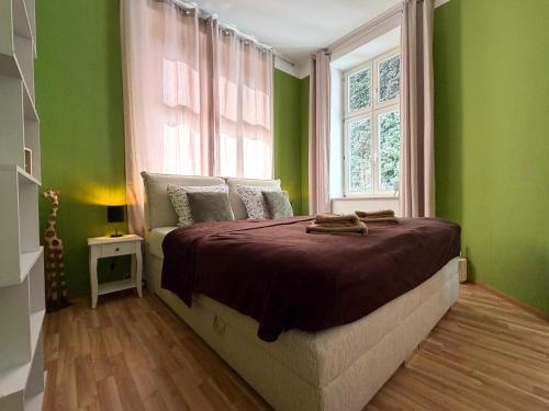 a bedroom with a bed with green walls and a window at Ferienwohnung am Altmarkt, für bis zu 4 Personen, 55qm in Cottbus