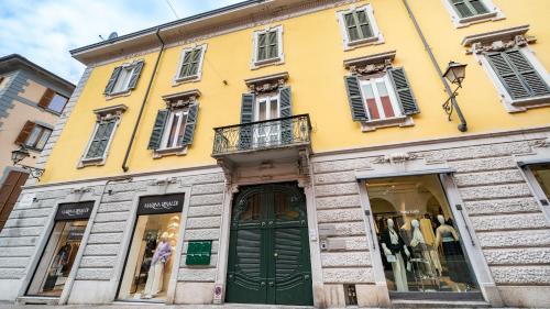 a yellow building with a green door and windows at Mariposa in Lecco