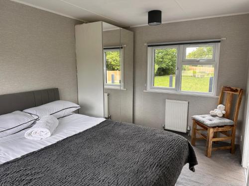 a bedroom with a bed and a chair and two windows at Toad Hall Suite in Chelmsford