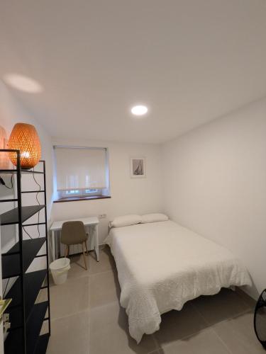 a white bedroom with a bed and a desk at PisoCentro in Santander