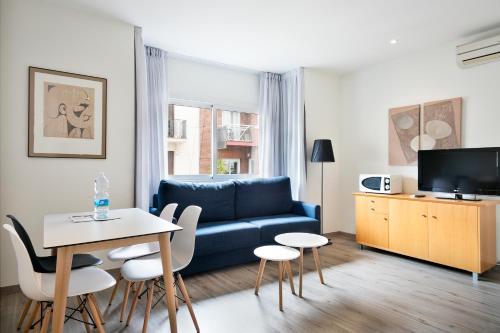 a living room with a blue couch and a table at Apartamentos Laforja in Barcelona