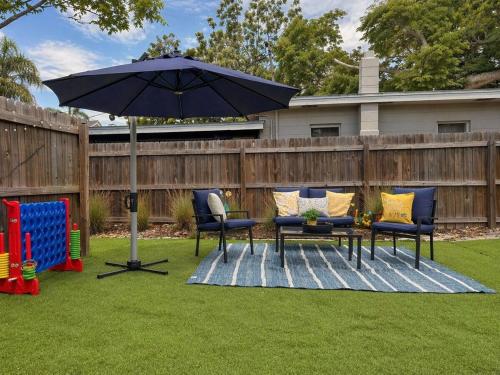 a patio with chairs and an umbrella in a yard at NEW Beach Cozy Bungalow 2B Mins-beach&downtown in Clearwater