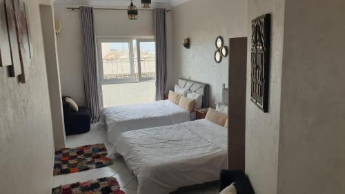 two beds in a small room with a window at Beach apartment down town in Agadir