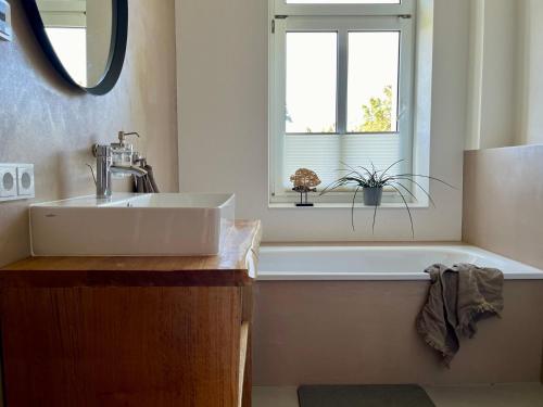 a bathroom with a sink and a tub and a window at Wohlfühl-Apartment Elbtal in Radebeul