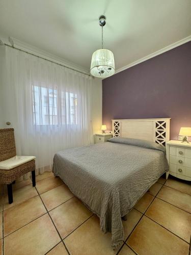 a bedroom with a bed and a chair and a chandelier at Rosa Somhome in Peniscola